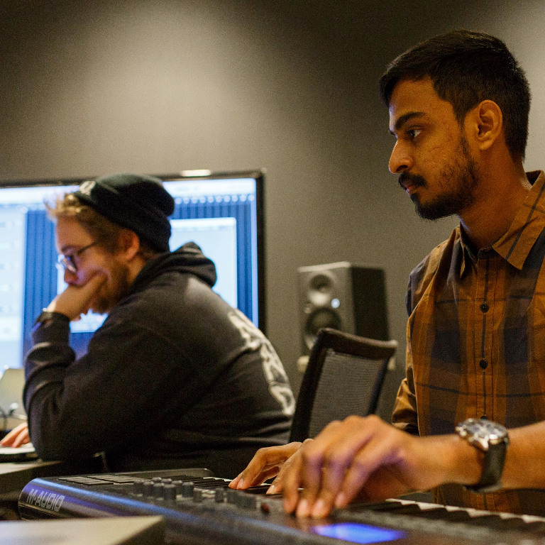 Color photograph of the two students working on music projects in the Tavel Center at Herron School of Art and Design.
