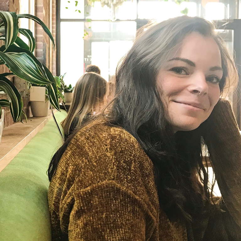 Meredith Haddan reclining in a cafe with plants in the background.